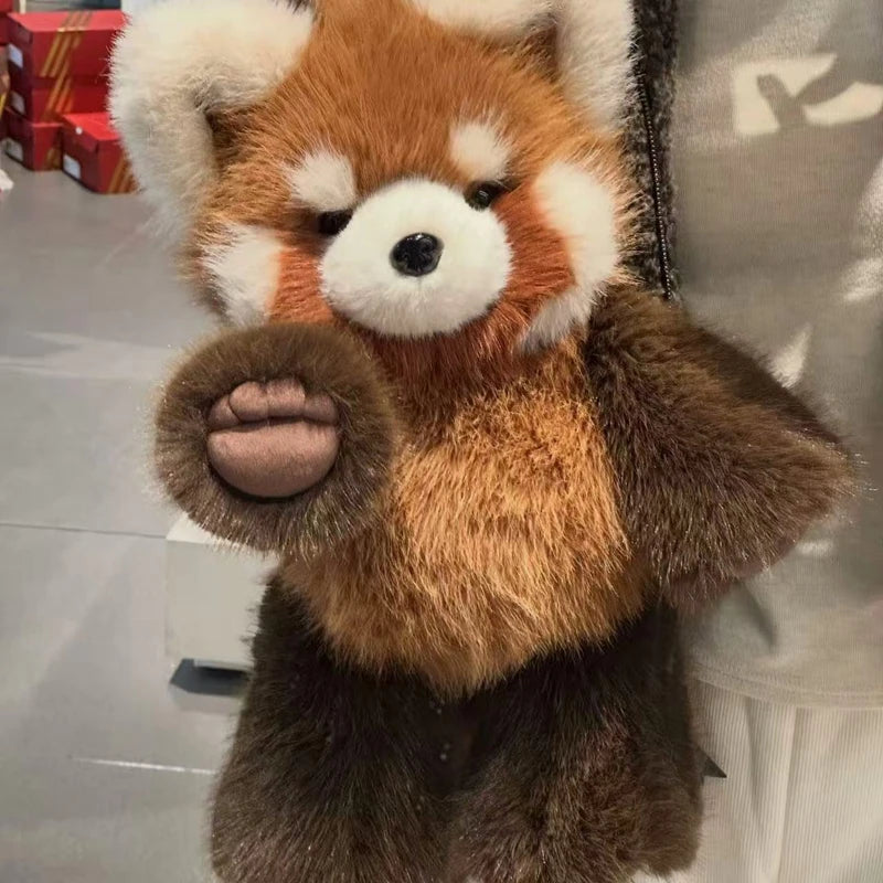 Plush toy red panda held by a person in an indoor setting