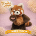 A plush red panda toy from Running Plusies sits on a soft pink surface with decorative floral props and a yellow banner reading LIMITED EDITION. The logo appears in the top left corner.